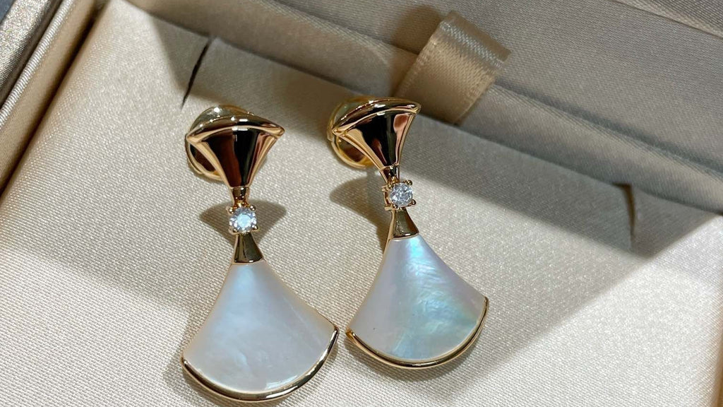 Pair of gold and white earrings in a jewelry box